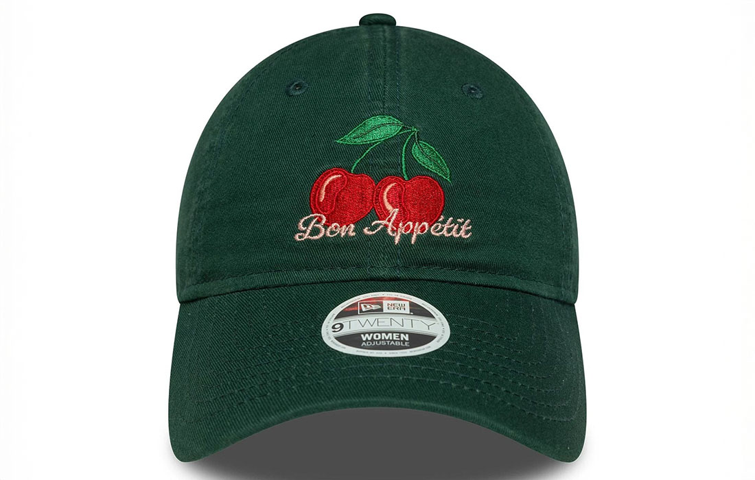 60691298_1_front Women New Era Phrase Dark Green 9TWENTY Cap Cherry graphic with Bon Appetit (Enjoy Your Meal) wordmark in French on front New Era Flag embroidered on left Unstructured crown Strapback Curved visor 100% COTTON Product ID: 60691298